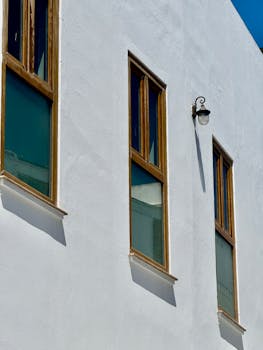 Minimalist facade with wooden windows in Cádiz, Spain, showcasing Mediterranean architecture.