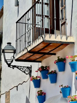 Sunny Andalusian balcony adorned with vibrant blue flower pots in Málaga, Spain.