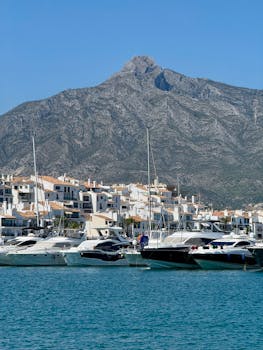 Scenic view of luxury yachts in Puerto Banús, Marbella with La Concha mountain backdrop on a clear day.