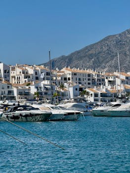 Beautiful sunny day at Marbella Marina with yachts and iconic whitewashed buildings in Málaga, Spain.
