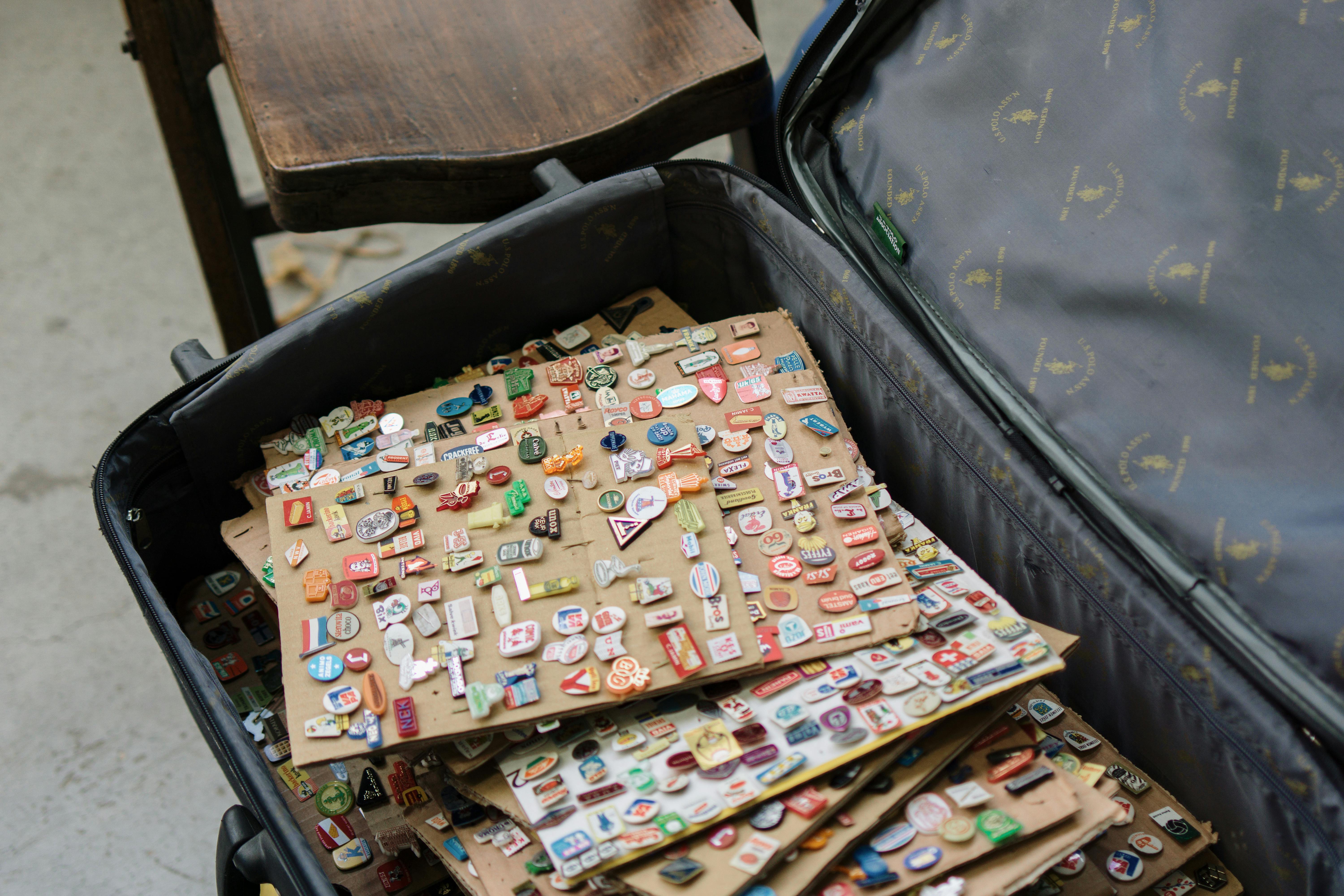 A suitcase full of vintage enamel pins, showcasing various designs and colors, ideal for collectors.