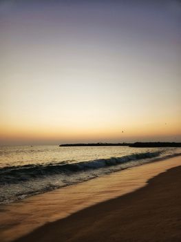 Serene sunset over a beach with gentle waves softly crashing on the shore.