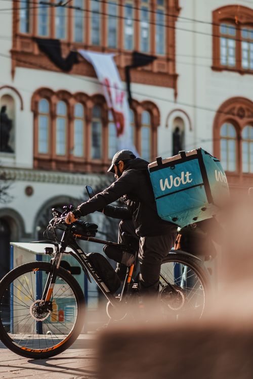 Free A delivery cyclist navigates the streets in Serbia, with historical architecture in the background. Stock Photo