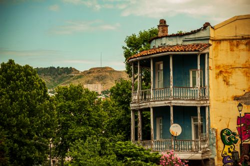 Free Historic balcony with ornate details against a scenic hillside backdrop, capturing urban decay charm. Stock Photo