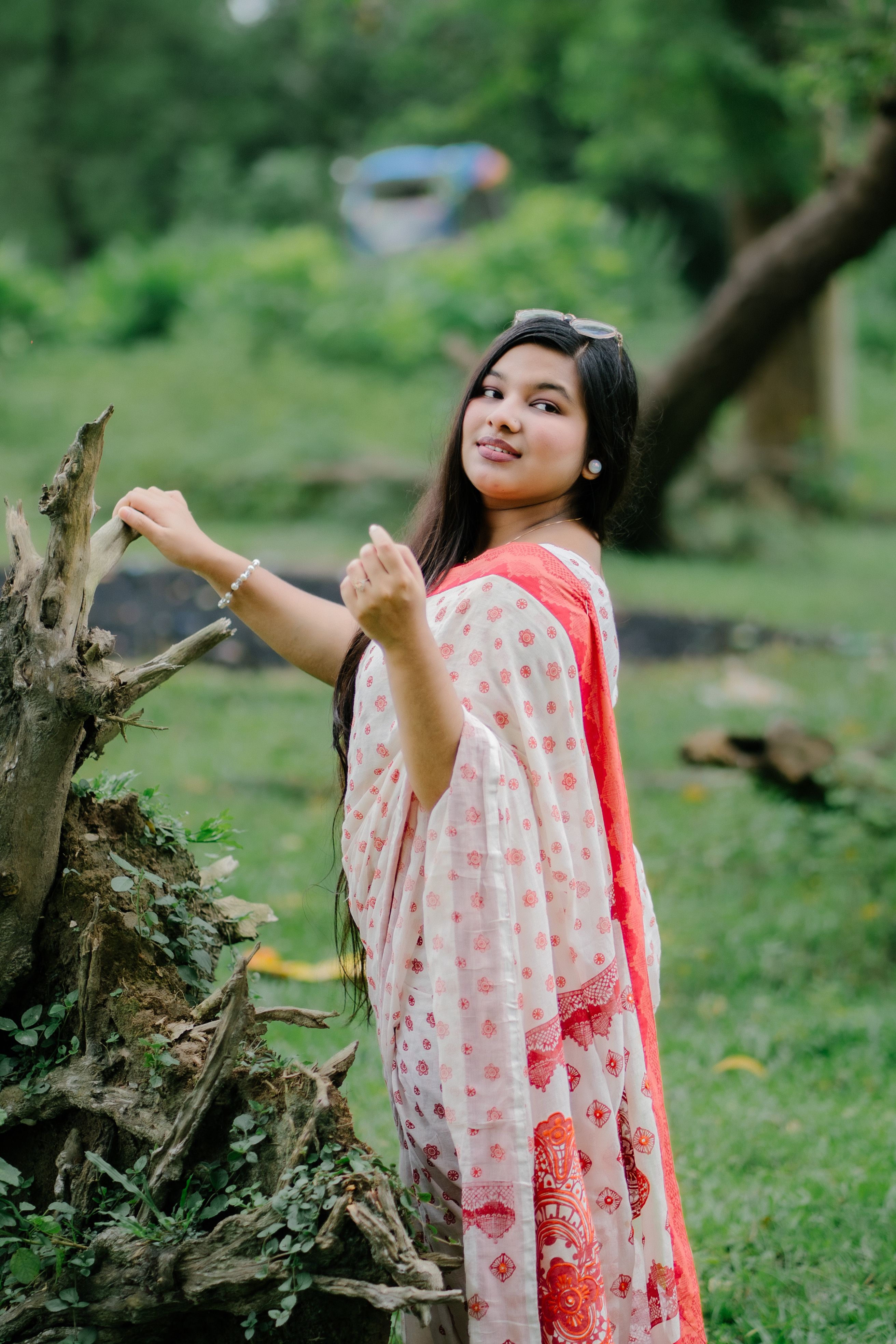 Woman in a saree enjoying a peaceful moment in a lush green park.
