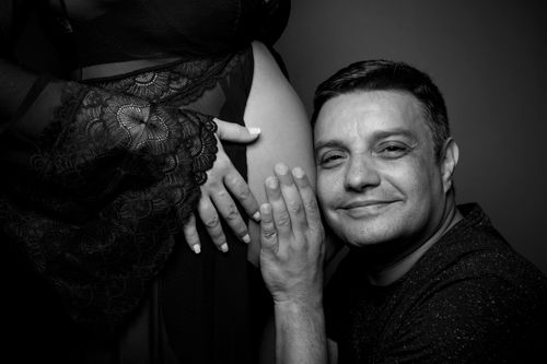Free A loving expectant father embraces his partner's baby bump in a monochrome portrait. Stock Photo
