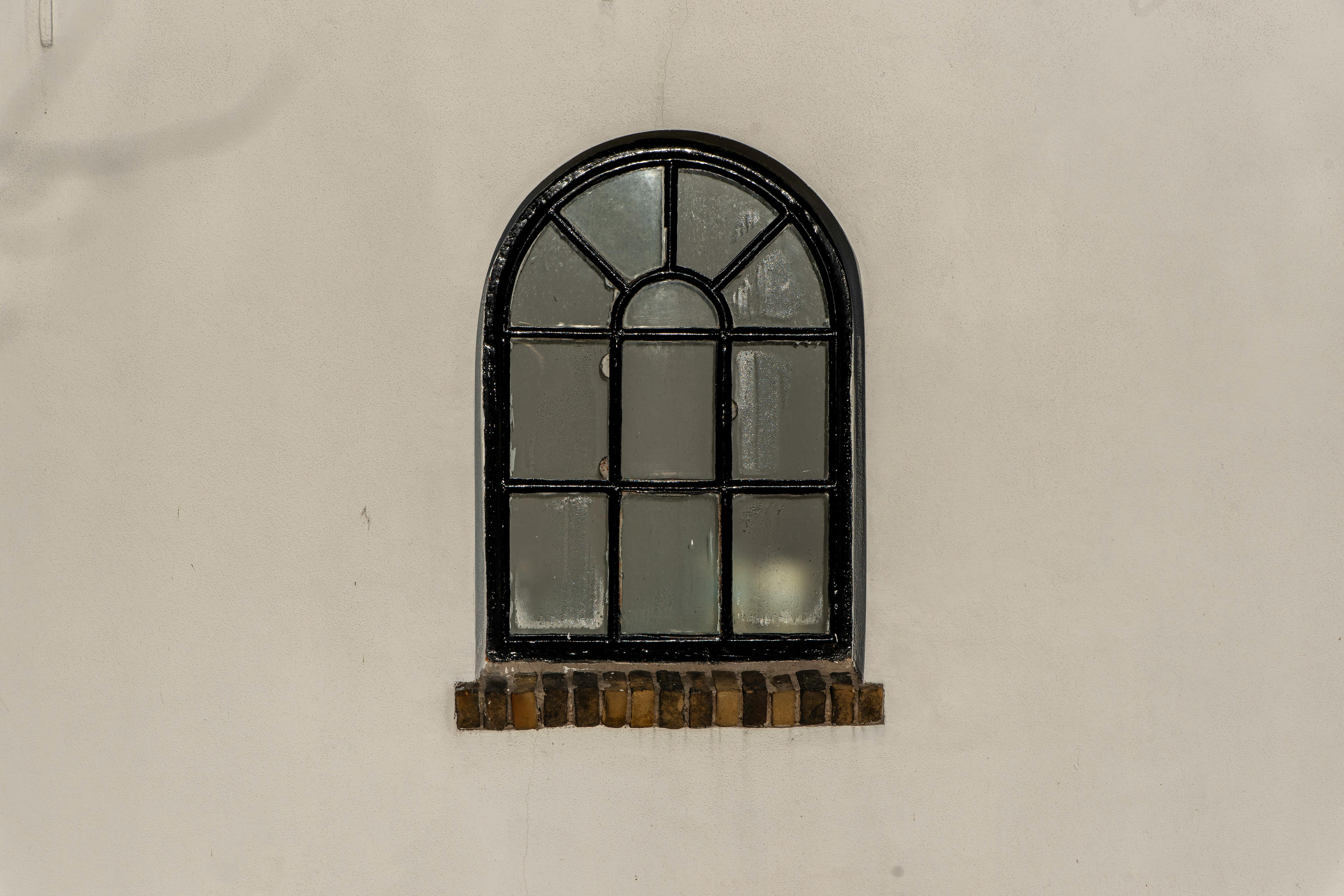 gratis Een klassiek boograam met een zwart kozijn op een lichtgekleurde muur. Stockfoto