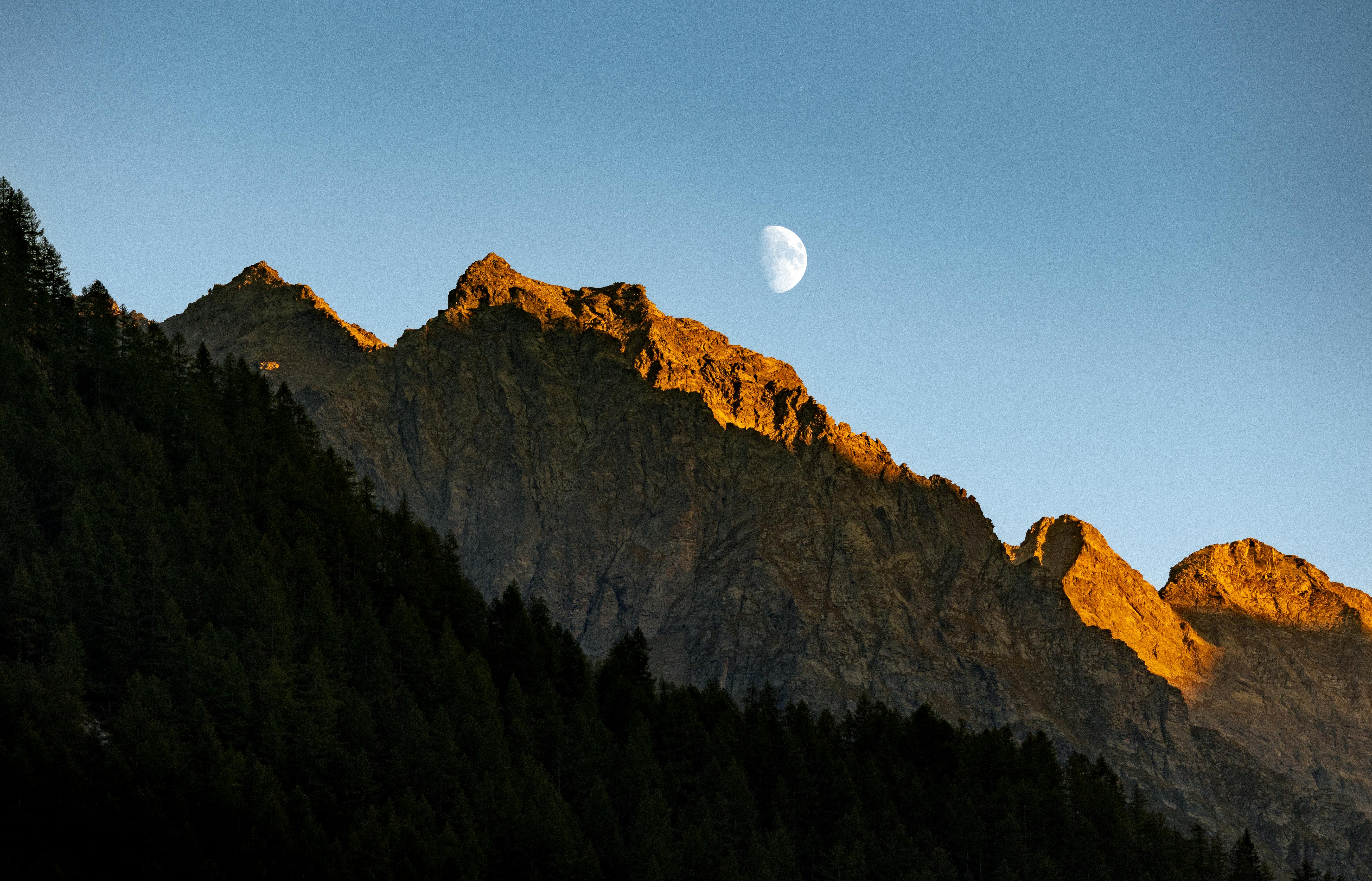 在意大利奥斯塔山谷升起的月亮下，阳光明媚的山脉展现出壮丽的景色