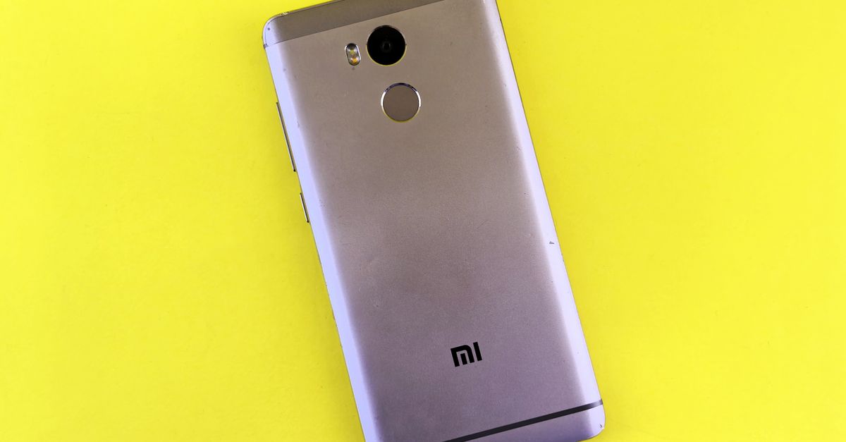 Um smartphone prateado sobre um fundo amarelo brilhante, exibindo um design elegante.