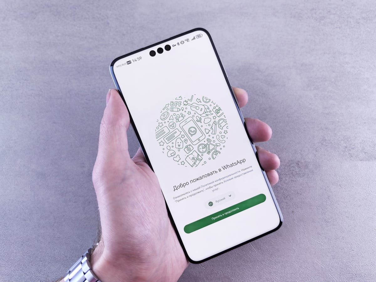 Primo piano di una mano che tiene uno smartphone con schermata WhatsApp