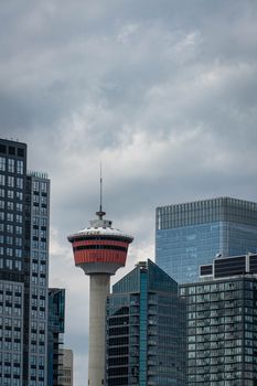 The iconic Calgary Tower amidst modern skyscrapers under a cloudy sky.