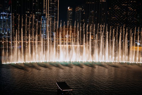 Free Illuminated water fountain show at night in downtown Dubai, surrounded by skyscrapers. Dubai Fountain Show