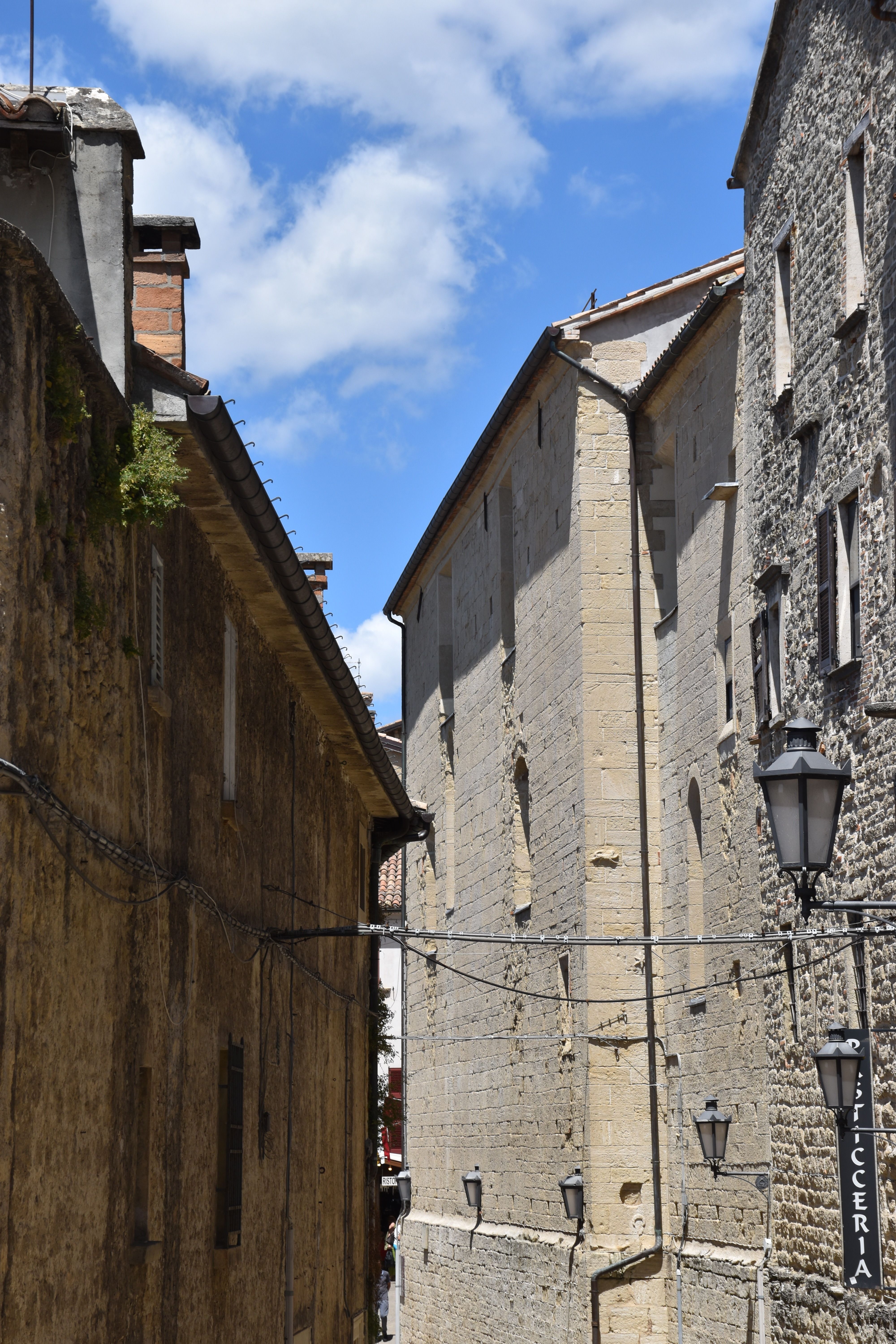 Explore a quaint, sunlit alleyway with historic architecture in San Marino.