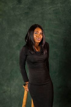 Elegant portrait of a woman in a black dress against a dark backdrop, showcasing style.