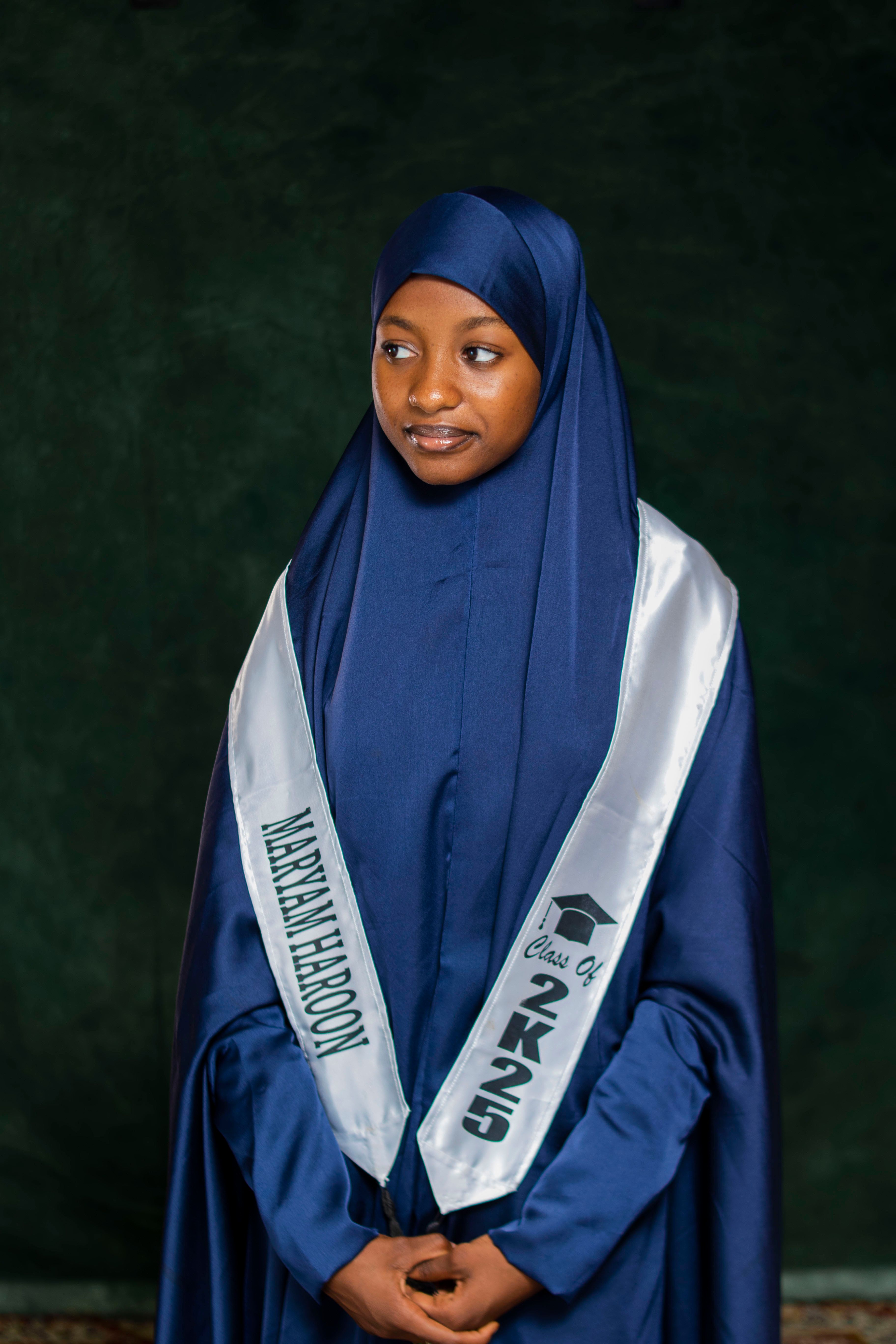 Young woman in hijab with graduation sash, portrait style.