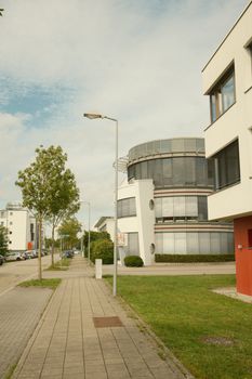 Street view of modern architecture and buildings with green space under a blue sky.