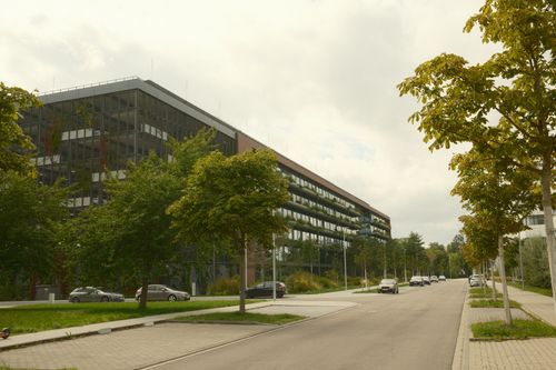 Free A sleek modern office building along a quiet tree-lined street. Stock Photo