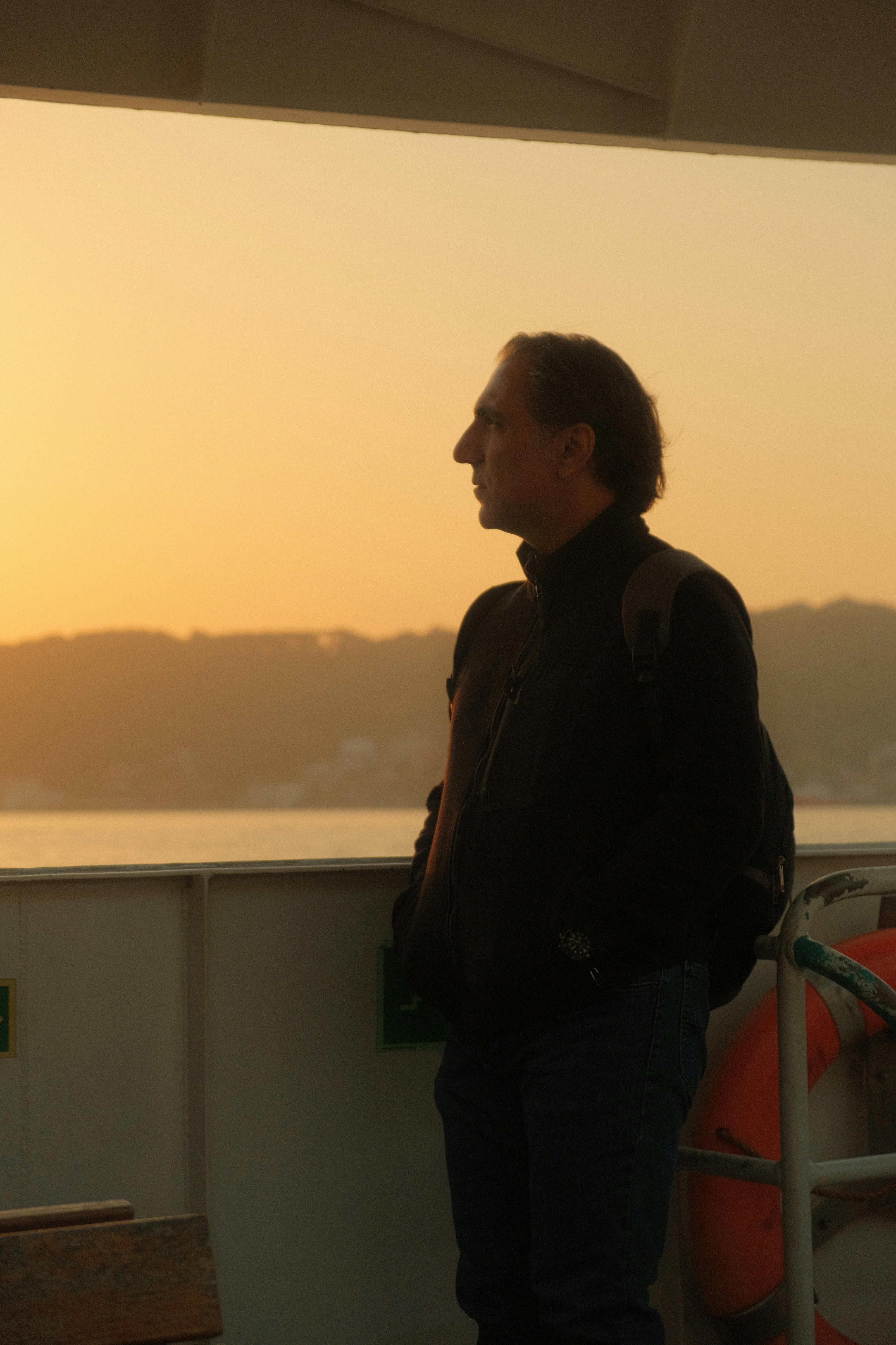 A man enjoys a tranquil morning ride on a ferry in Istanbul, as the sunrise paints the Bosphorus with golden hues.