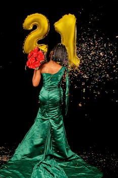 A woman in a green dress celebrates her 21st birthday with balloons and confetti.