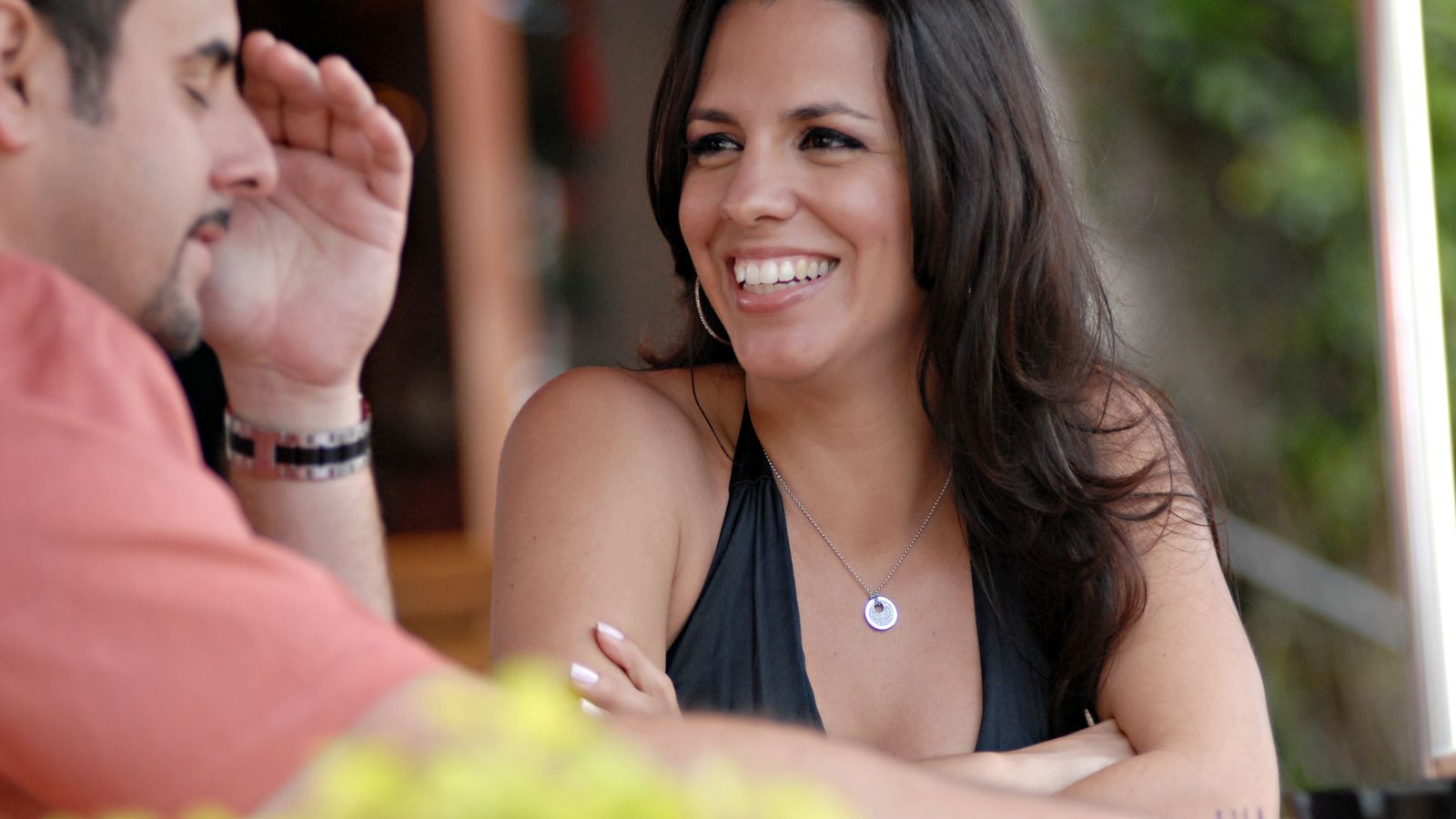 Two adults talking across an outdoor café table