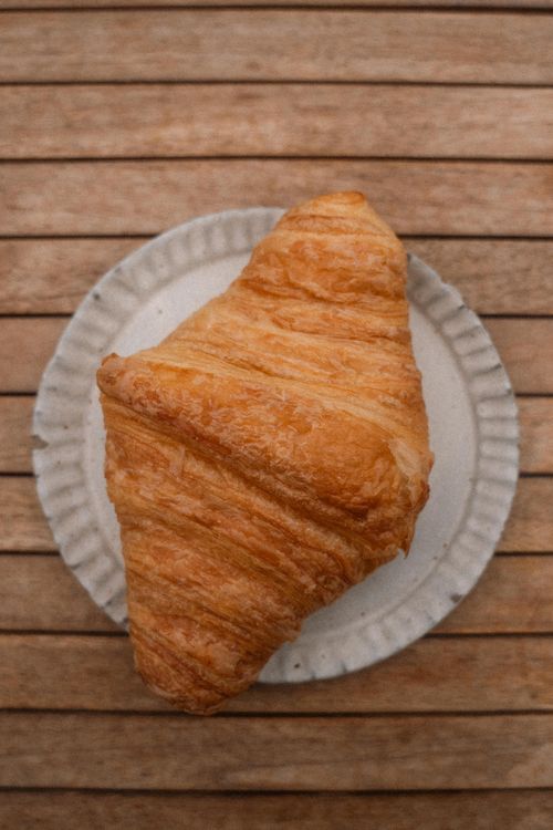 Free Freshly baked croissant on a rustic plate, perfect for breakfast visuals. Stock Photo