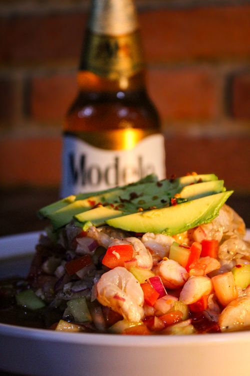 Free Close-up of shrimp ceviche with avocado slices, accompanied by a beer bottle. Stock Photo