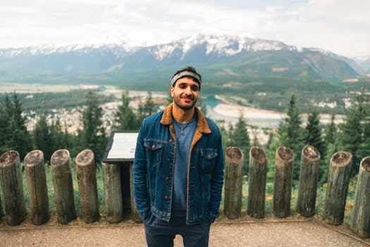 Man stands smiling with mountains in the background, Revelstoke, Canada.