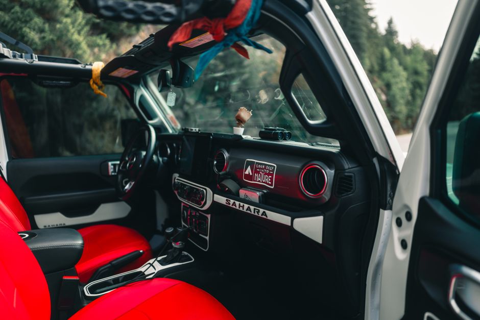 Interior of a rugged adventure vehicle with vibrant red seats, set in a lush forest backdrop.