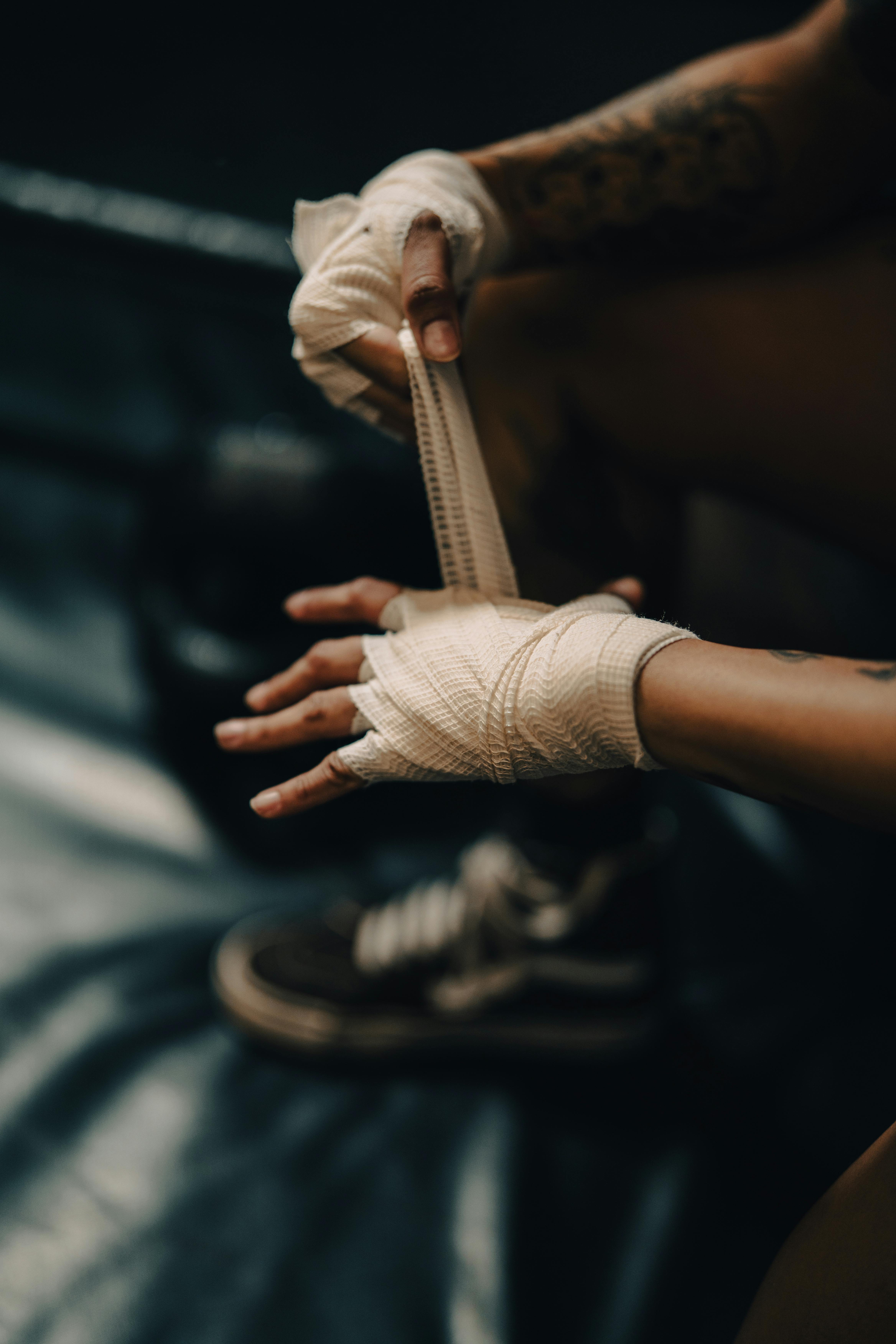 Close-up of a boxer's hands being wrapped with bandages in a gym setting, ready for training or a match.