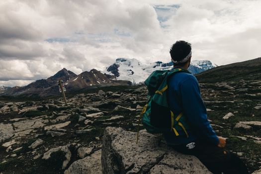 A lone hiker with backpack takes in the stunning mountain scenery in Jasper National Park, Alberta, Canada.