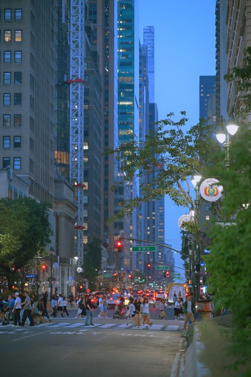 Free A lively street scene at dusk in New York City, framed by towering skyscrapers and bustling pedestrians. Stock Photo