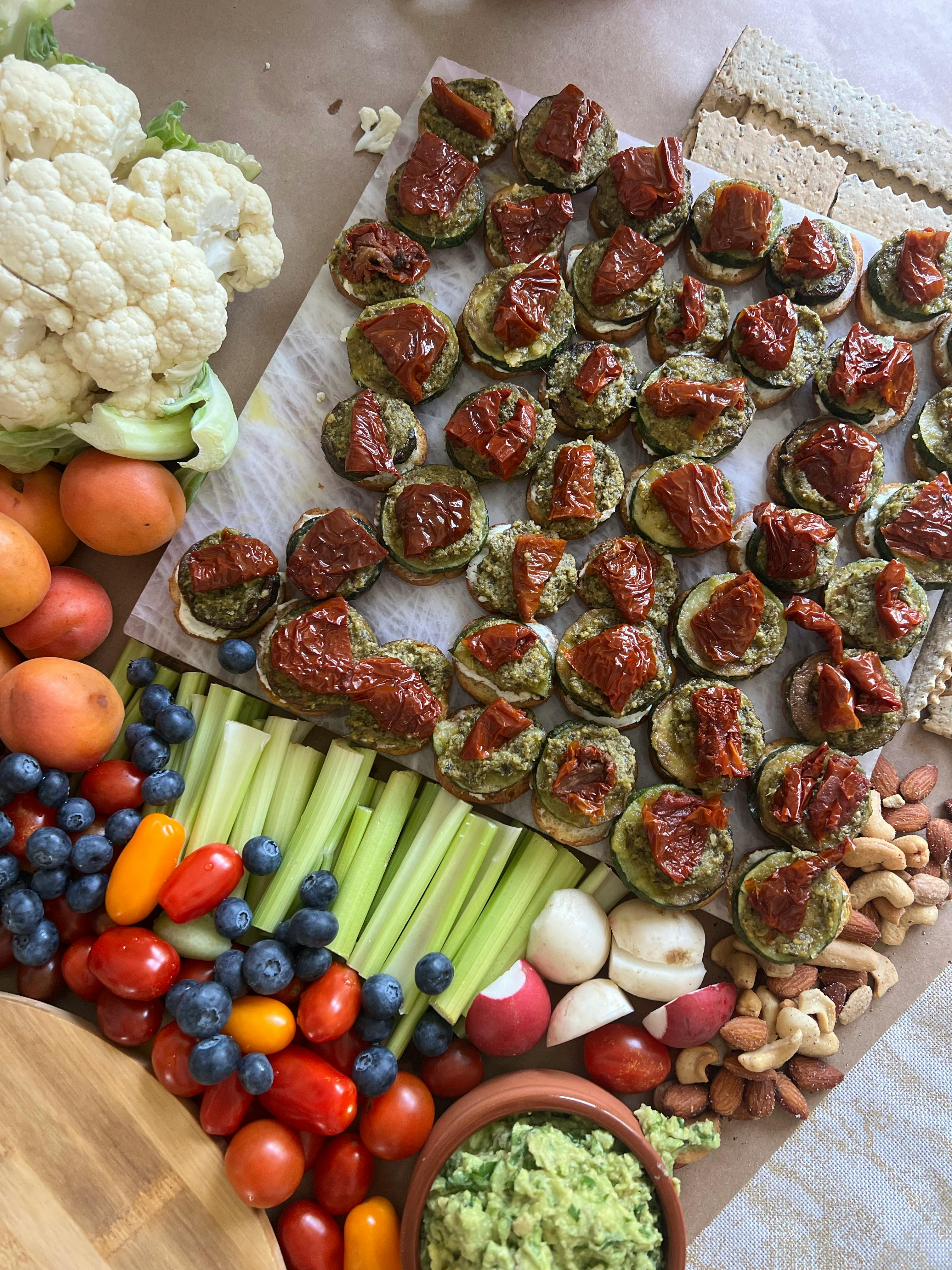 Colorful vegan platter with assorted veggies, fruits, nuts, and sun-dried tomato bites.