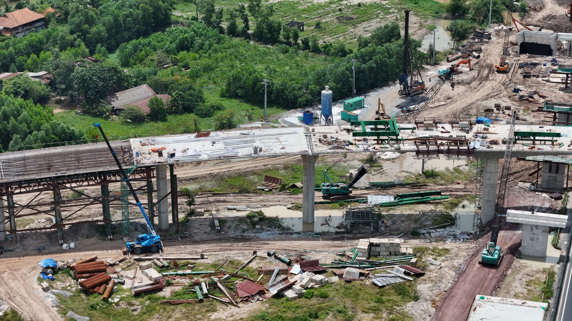 Aerial shot showing the construction of a bridge in a rural area of Vietnam, highlighting the progress and machinery involved
