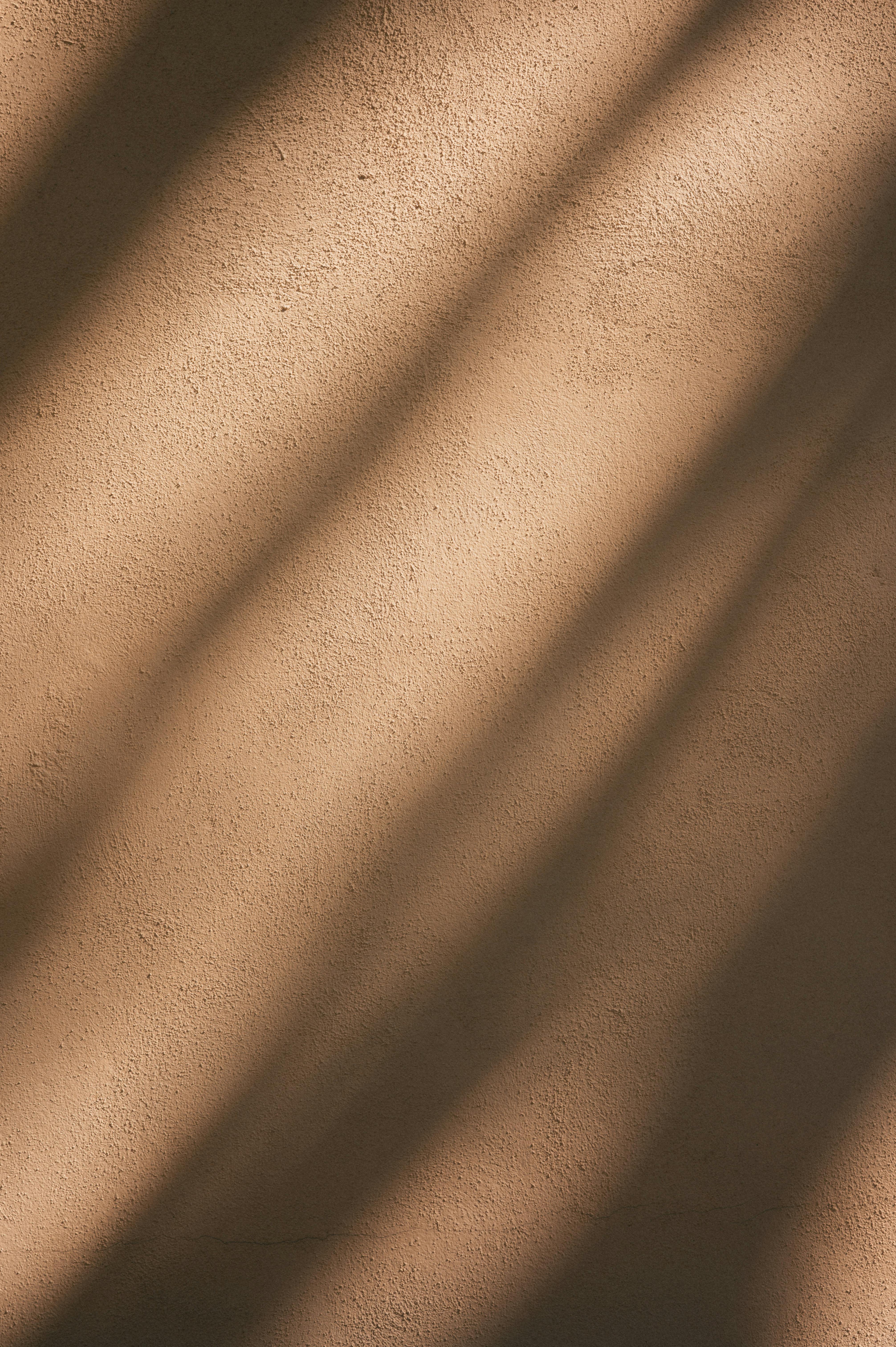 Kostenlos Weiche Schatten und Sonnenlichtmuster erzeugen einen abstrakten Effekt auf einer strukturierten Wand. Stock-Foto