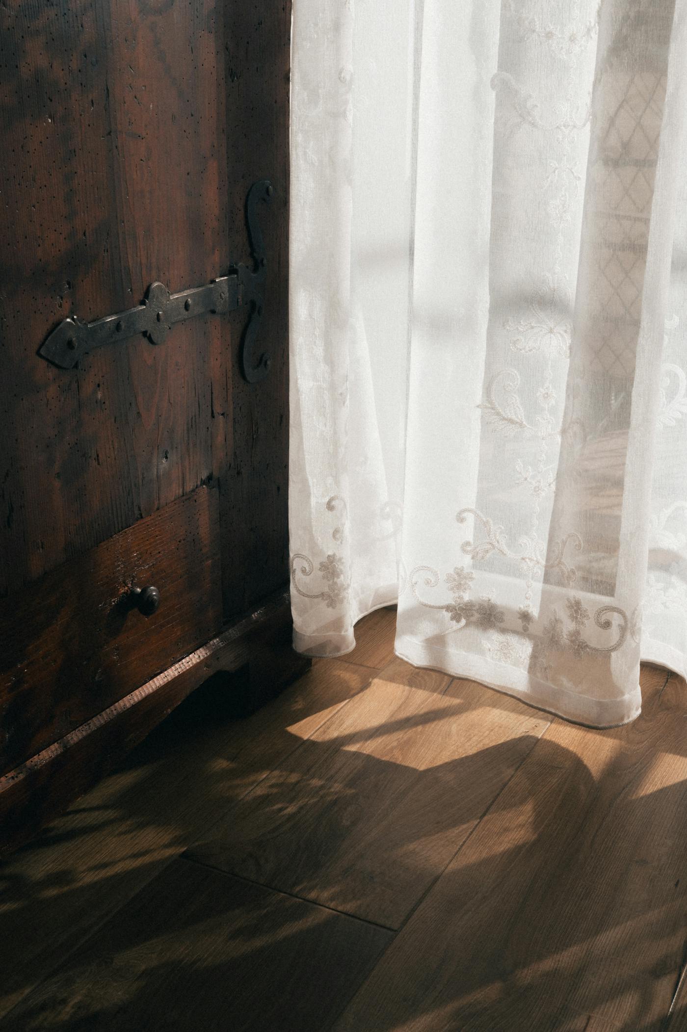 Stanza illuminata dal sole con tende di pizzo e mobili in legno