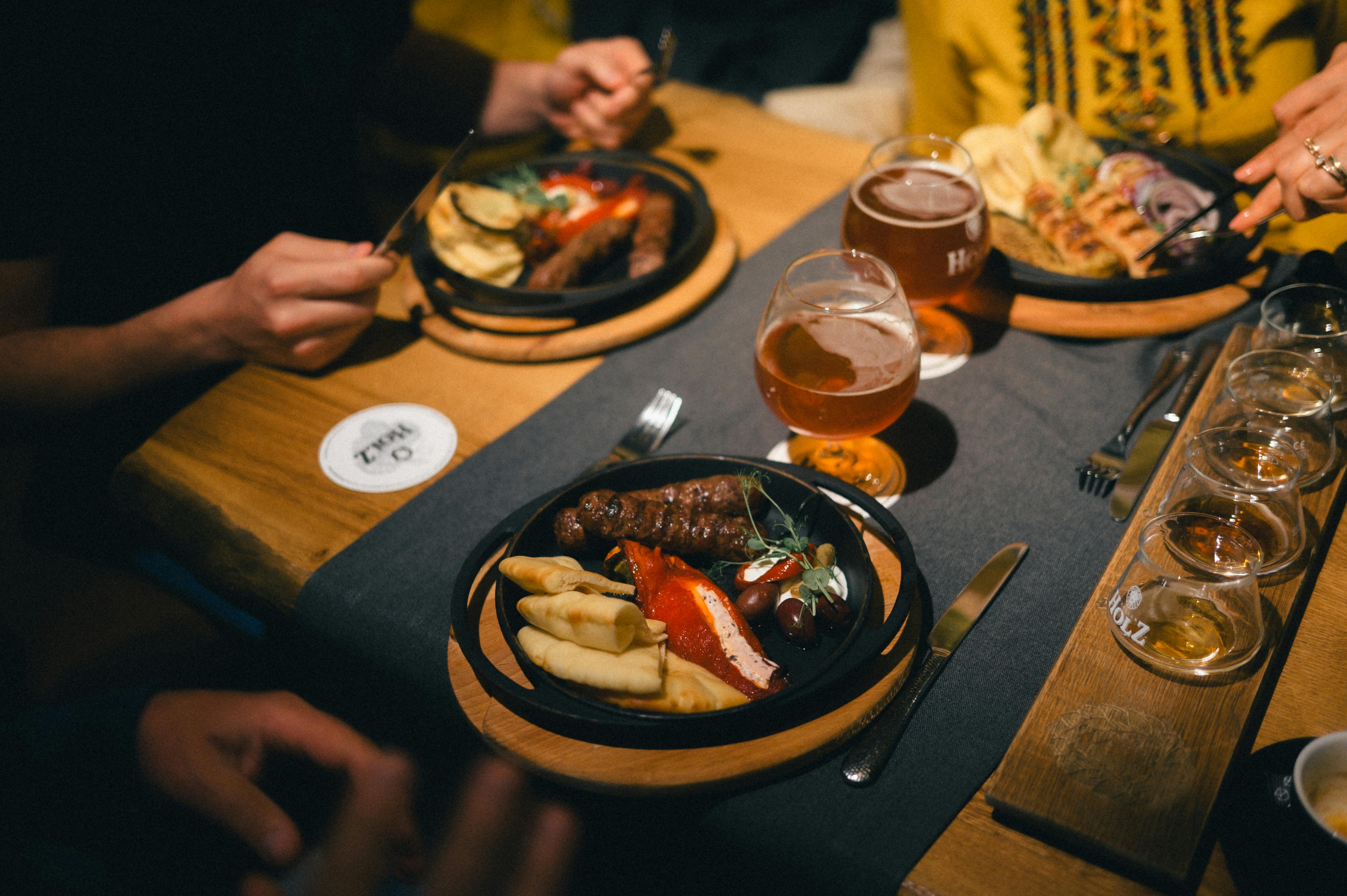 Friends enjoying a casual meal with beer and diverse platters in a cozy setting.