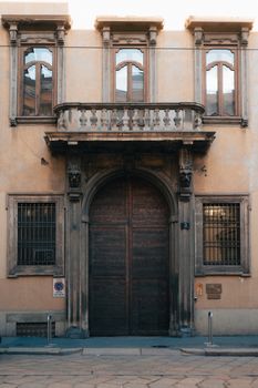 A classic European building entrance with ornate architecture and a wooden door captured during the day.