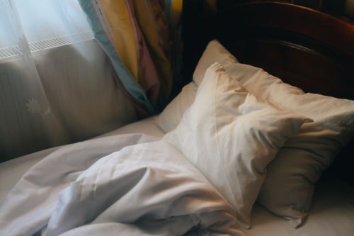 Free Inviting unmade bed with soft pillows in morning light, creating a cozy atmosphere. Stock Photo