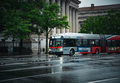 A Metrobus travels on a rainy street in Washington, DC, showcasing city life and urban transport.