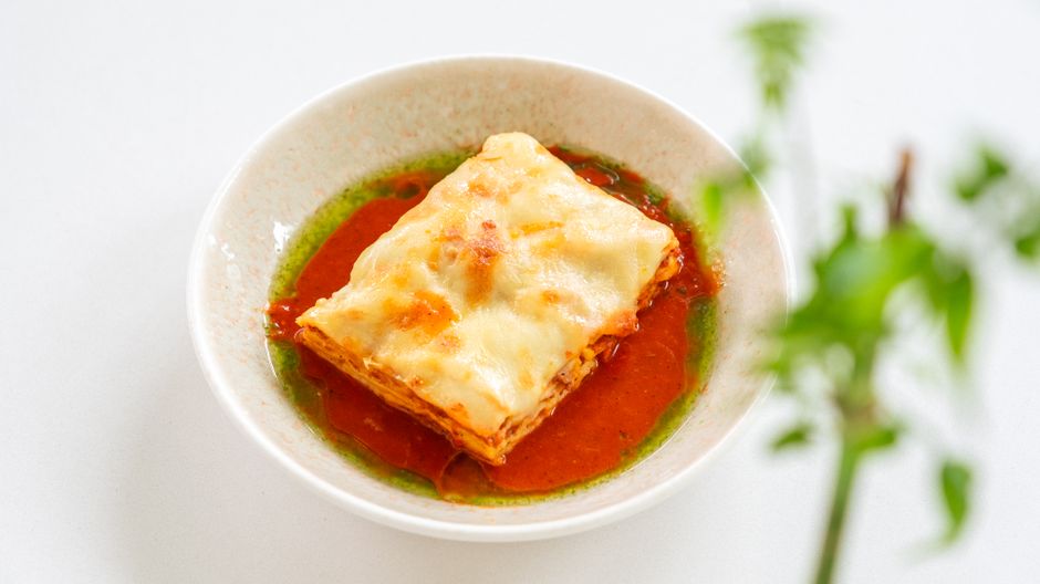 Homemade lasagna garnished with tomato and basil sauce, perfect for Italian cuisine lovers.