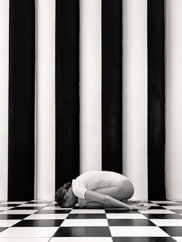 Artistic yoga pose in black and white against striped wall. Captivating and serene.