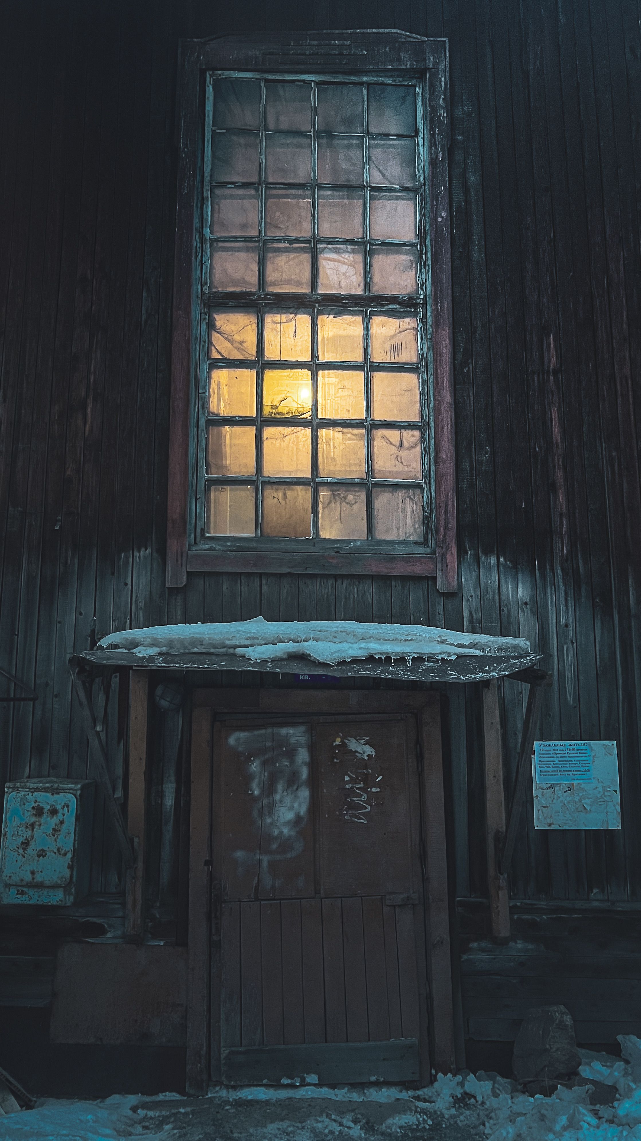 Free An old wooden door with a glowing window above, creating a mysterious nighttime ambiance. Stock Photo