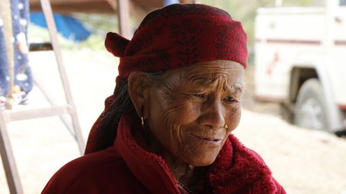 Free Portrait of an elderly woman in a red headscarf outdoors, expressing wisdom. Stock Photo