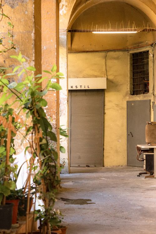 Free Rustic industrial corridor with greenery and closed metal shutters, perfect for urban themes. Stock Photo
