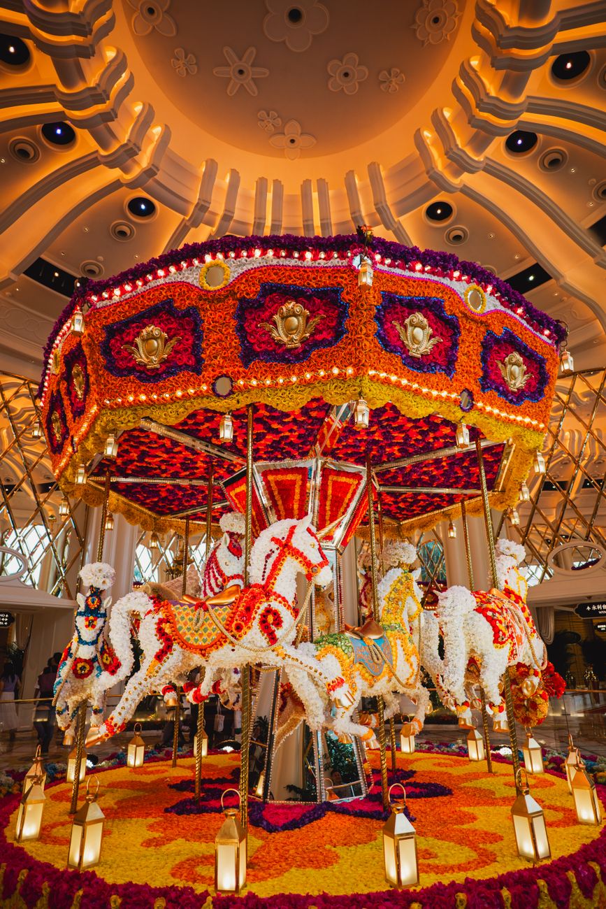 Image captivante d'un carrousel floral coloré à l'intérieur sous un éclairage ambiant chaleureux.