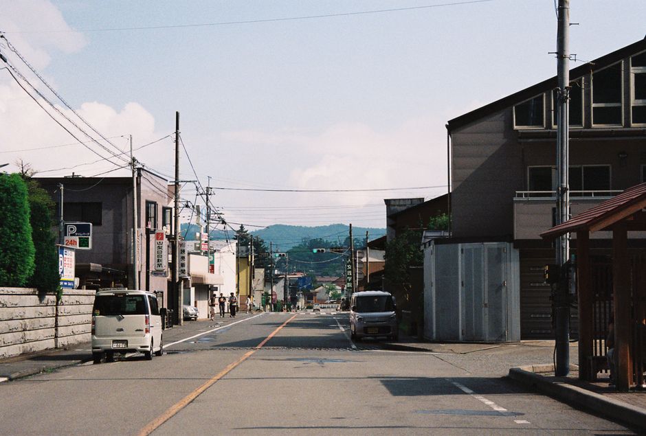 日本の山梨県にある、山々を背景に地元の建築物が並ぶ趣のある通り。