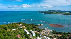 Stunning aerial view of a coastal town with lush greenery and vibrant blue ocean waters.