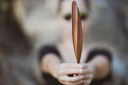 A close-up shot of a person holding a dried leaf, emphasizing nature's texture in fall.