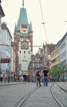 A bustling street scene featuring historic architecture and people walking in Freiburg, Germany.