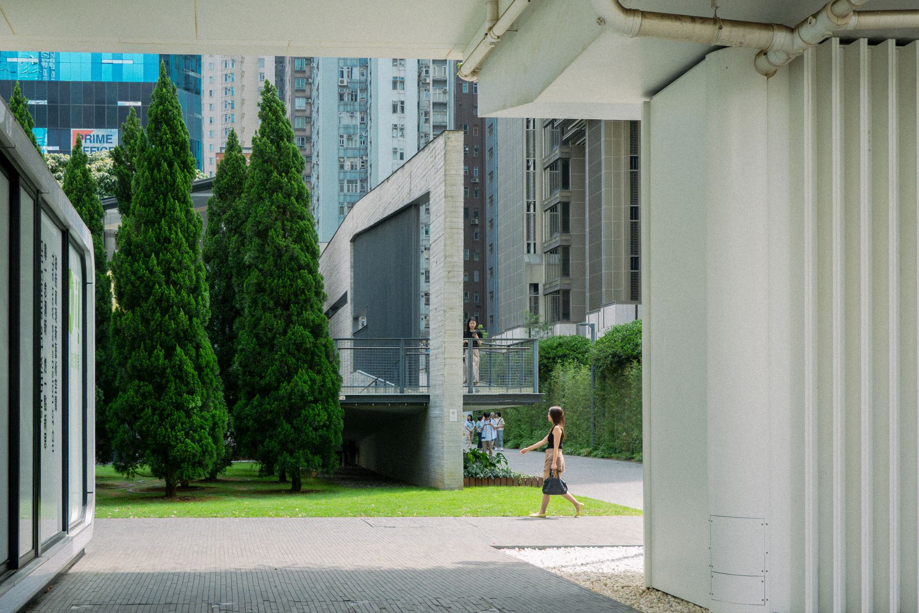 Woman walking through modern architecture in Hong Kong's urban landscape.